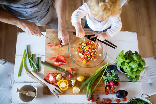 overhead view of child and adult preparing some healthy vegetables together