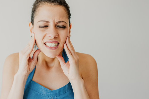 Woman holding her face in pain