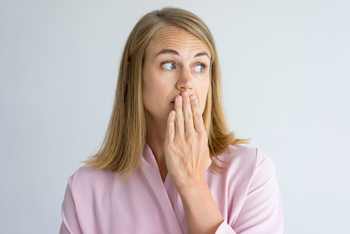 Woman with bad breath holding mouth