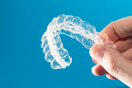 Hand holding clear aligner tray